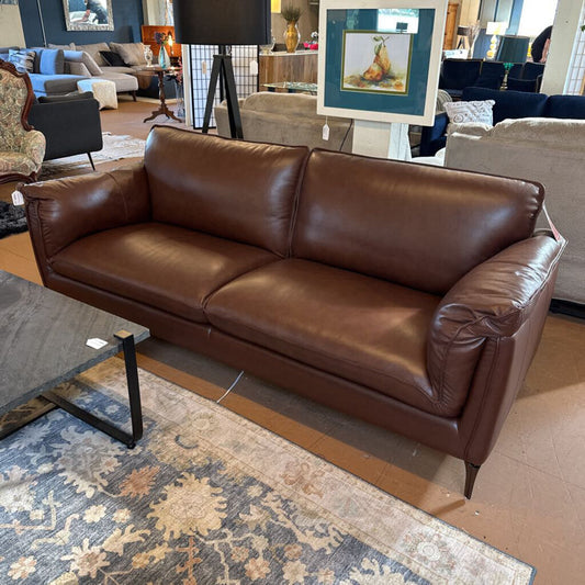 Brown leather sofa in a room with a rug and furniture.