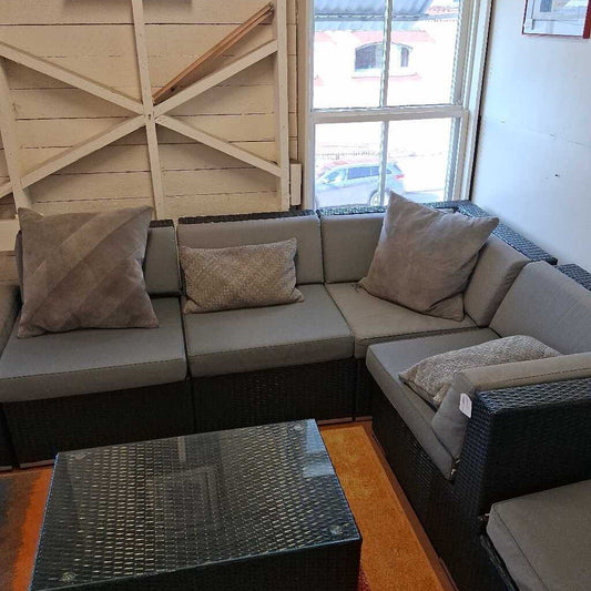 Sectional sofa with cushions in a room with wooden walls and a window.