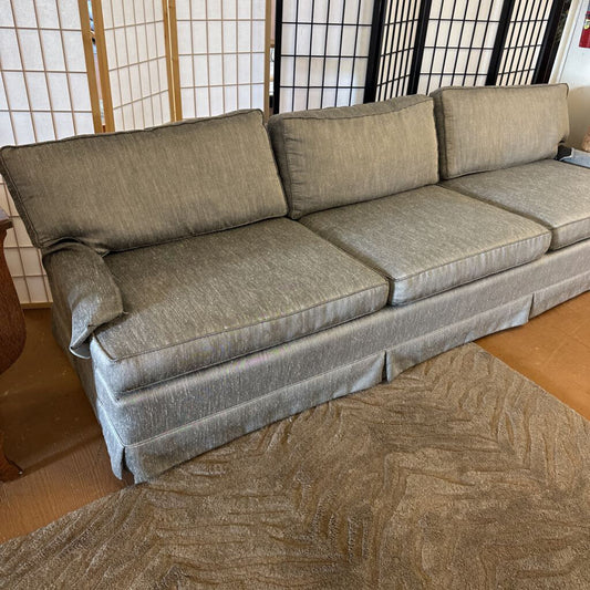 Gray sofa in a room with a wooden floor and a screen in the background