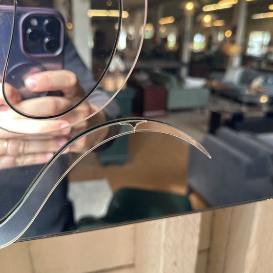 Close-up of a phone with a cracked screen held by a person in an indoor setting.