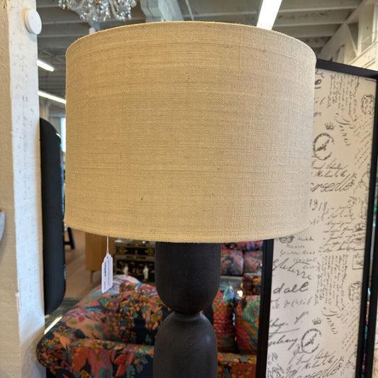 Beige lampshade on a dark base with a blurred indoor setting