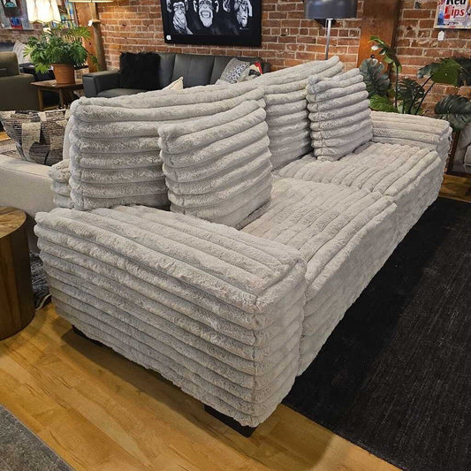 Gray textured sofa in a room with brick walls and decorative elements.