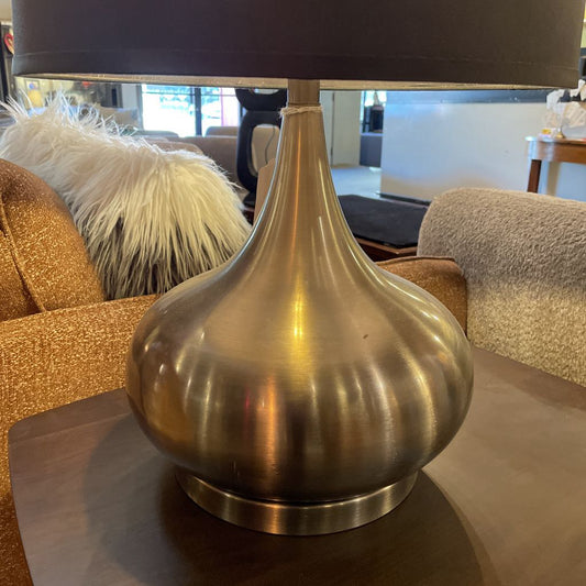 Bronze table lamp with a dark brown lampshade on a reflective surface.