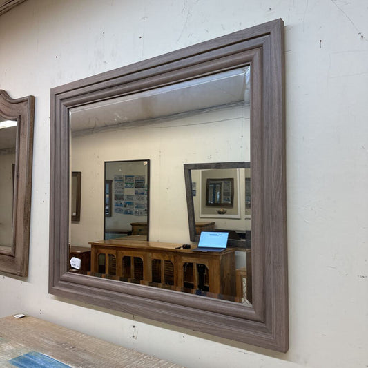 Wooden framed mirror on a white wall