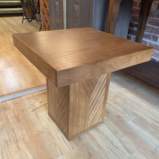 Wooden side table on a wooden floor with a brick wall in the background