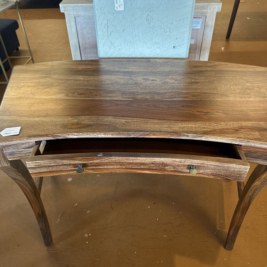 Wooden desk with a single drawer on a wooden floor.