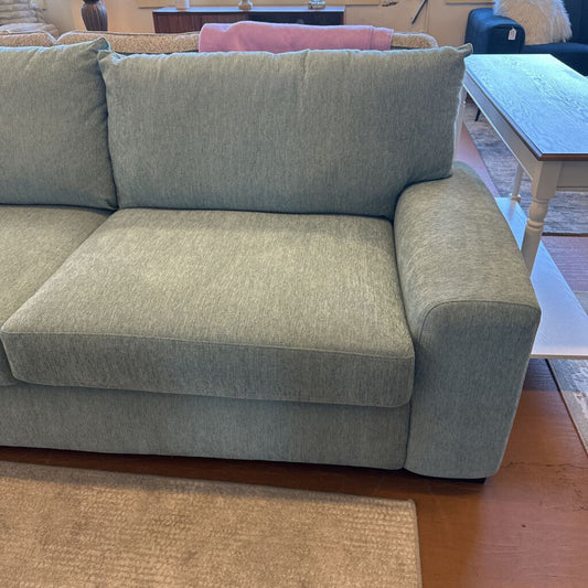 Gray sectional sofa in a living room setting with a wooden floor and furniture.