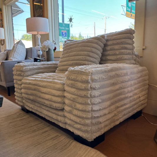 Beige plush sofa in a room with large windows showing an outdoor view.