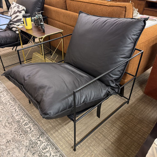 Black cushioned chair with metal frame in a living room setting