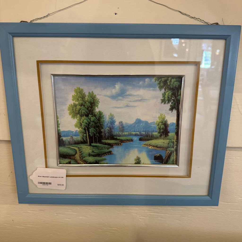 Framed landscape painting with a blue border on a white wall.