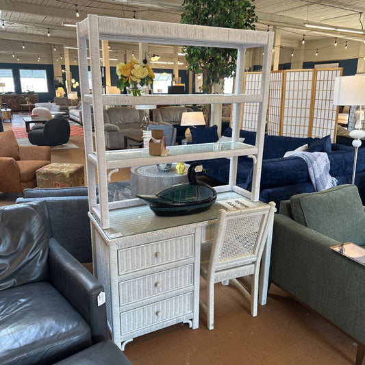 Furniture display with a white rattan shelf, chairs, and sofas in a showroom setting.