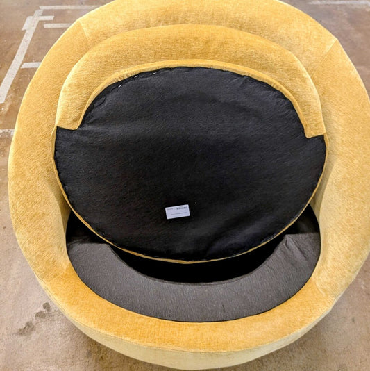Round yellow pet bed with a black interior on a concrete floor.