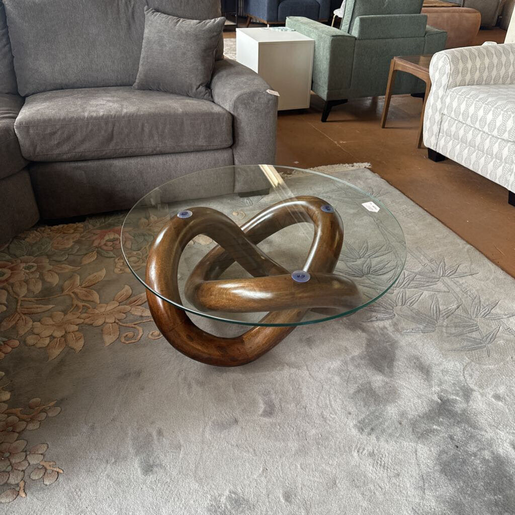 Glass coffee table with wooden base in a living room setting