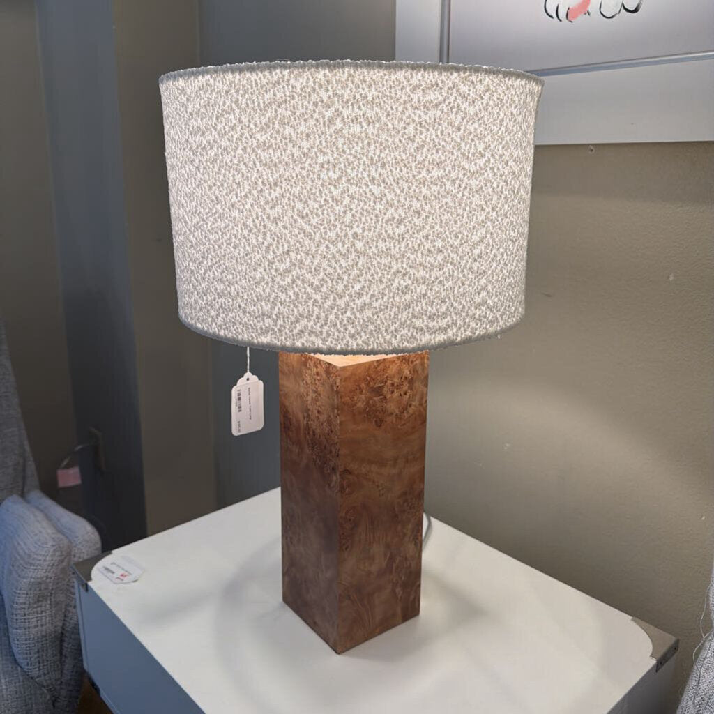 Table lamp with a textured shade and wooden base on a white surface.