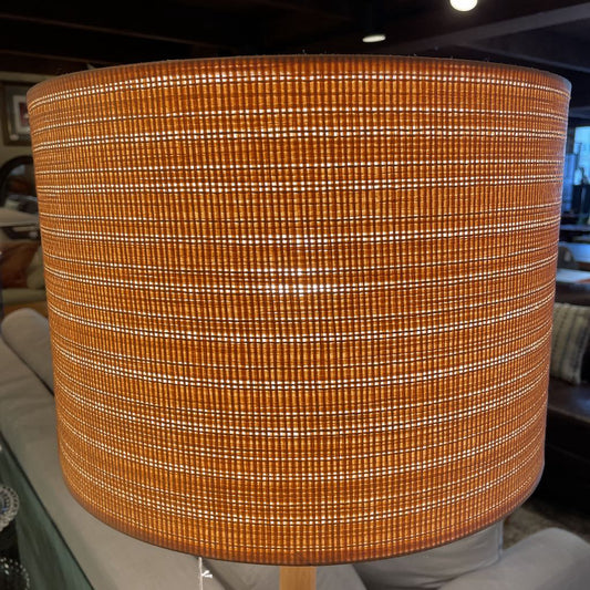 Round woven lampshade with a plaid pattern on a stand.