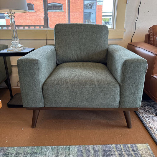 Green armchair in a room with a window and furniture.