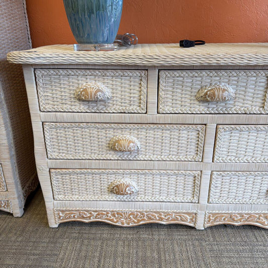 Wicker dresser with shell-shaped knobs against a wall.