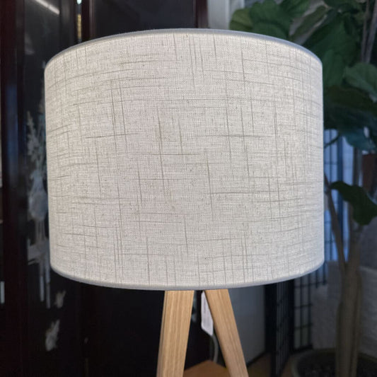Lamp with a textured gray shade on wooden legs in an indoor setting
