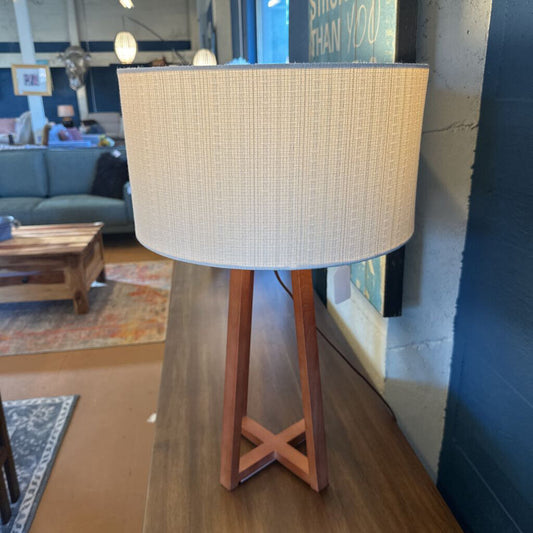 Lamp with a textured beige shade on a wooden stand in a living room setting.
