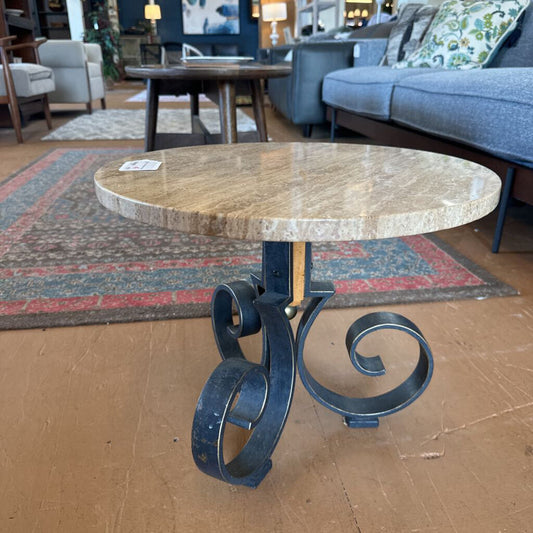 Round marble table with decorative metal legs in a furniture store setting