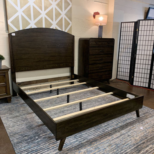 Dark wood bed frame with wooden slats on a blue patterned rug.