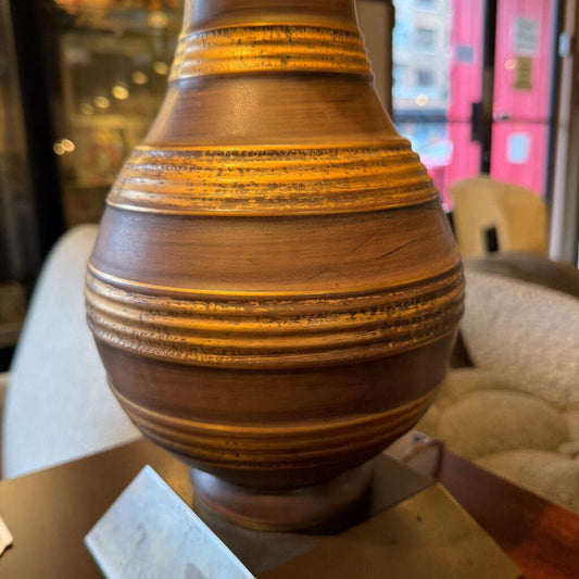 Wooden vase with concentric circular patterns on a blurred indoor background