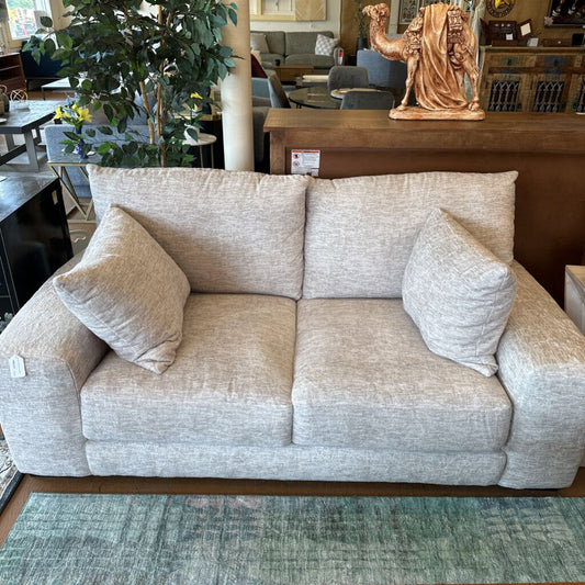 Beige sofa with decorative pillows in a furniture store setting