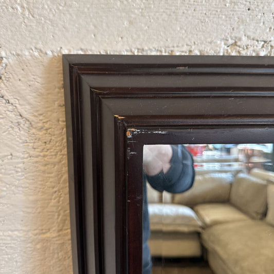 Close-up of a dark wooden picture frame against a textured wall.