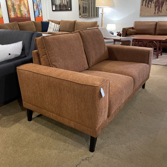 Brown sofa in a showroom with other furniture and decor.