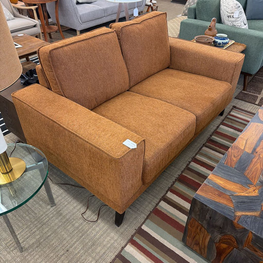 Brown sofa in a showroom setting with furniture and decor around.