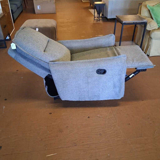 Gray recliner sofa on a wooden floor with a blurred background