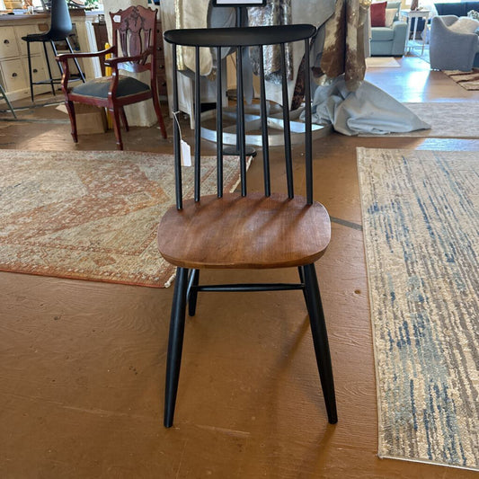 Wooden chair with black metal legs on a wooden floor.
