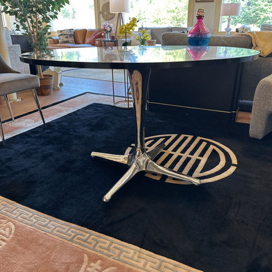 Modern living room with a round black table and decorative rug.