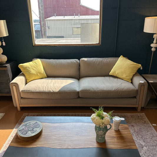 Living room with a beige sofa, yellow pillows, and a coffee table with a vase and cup.