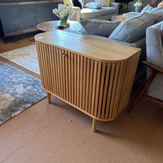 Wooden sideboard in a living room setting with a sofa and coffee table.