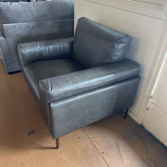 Gray leather sofa on a wooden floor with a neutral wall background