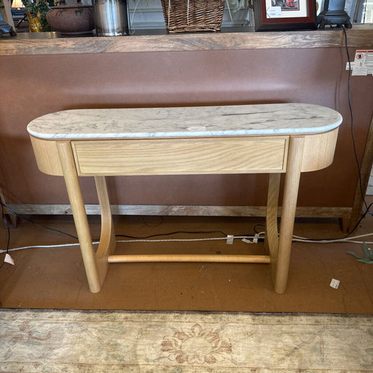 Wooden console table with marble top on a brown floor