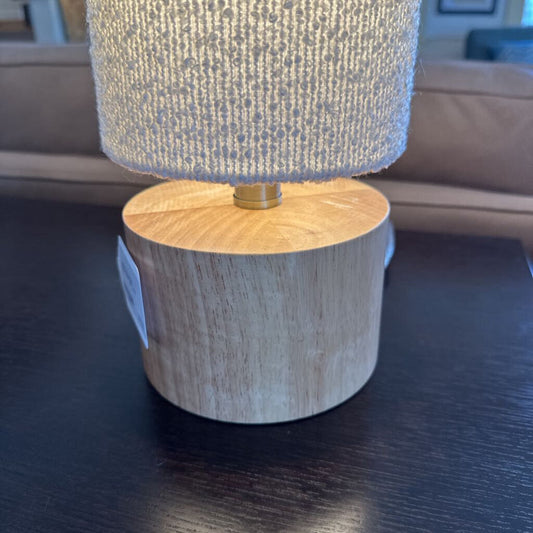 Table lamp with wooden base and textured gray shade on a dark surface.