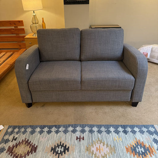 Gray sofa in a living room setting with a patterned rug.