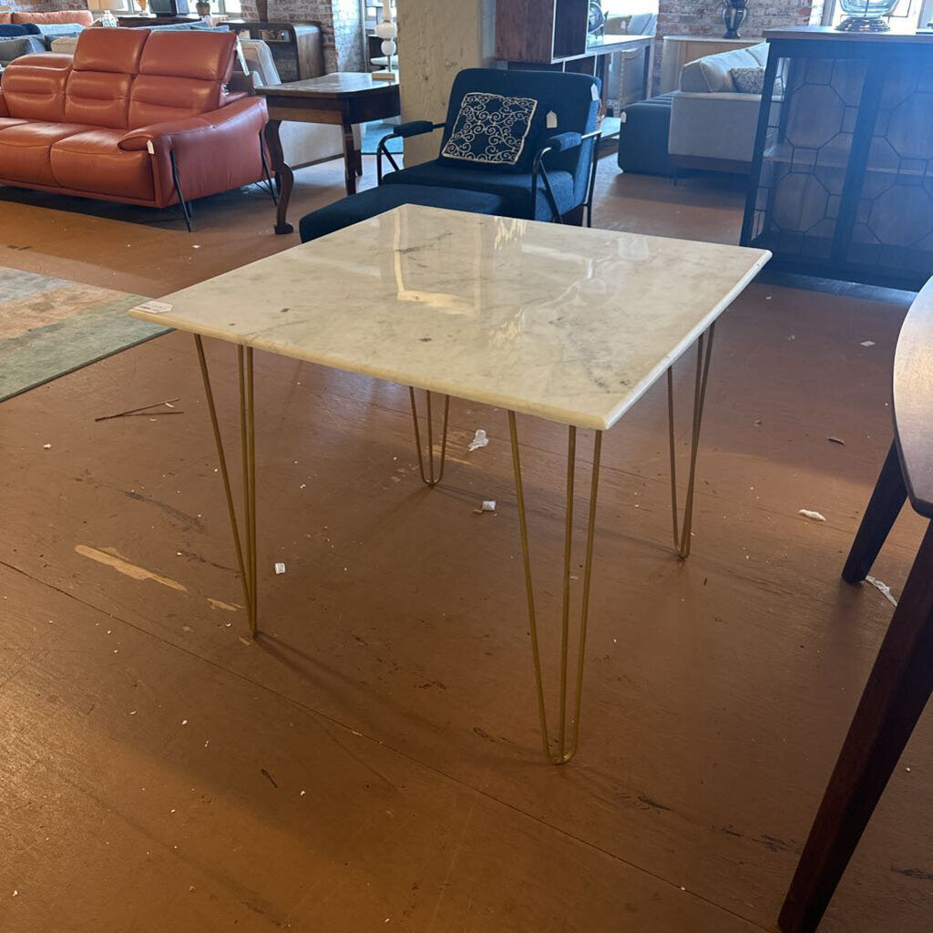 Dining table with marble top and metal legs in a room with furniture.