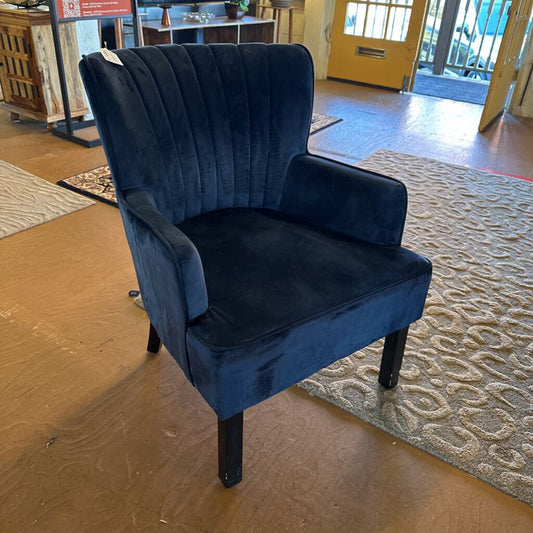Blue velvet armchair in a room with wooden flooring and a yellow door.