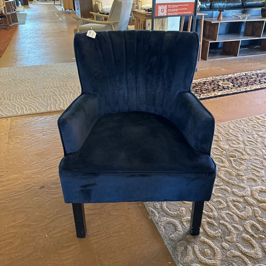 Blue velvet armchair in a showroom setting with flooring and furniture visible.