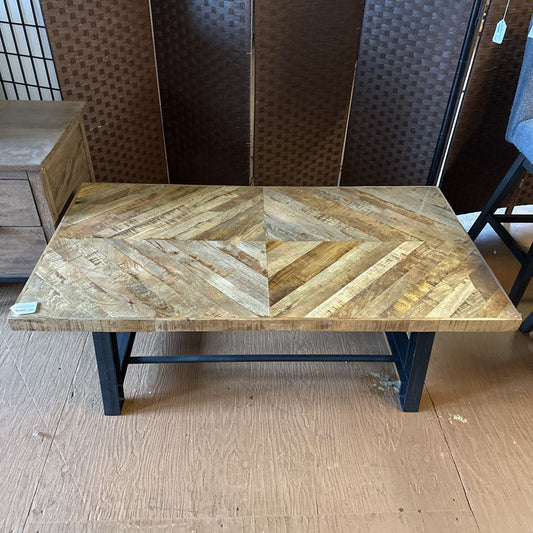 Wooden dining table with a herringbone pattern on a wooden floor.