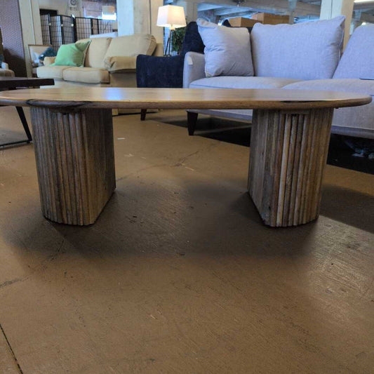 Wooden coffee table with cylindrical base in a room with furniture
