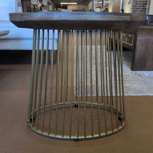 Round metal side table with a wireframe design on a carpeted floor.