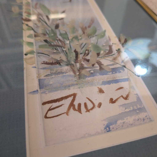 Card with nature-themed illustration and signature on a reflective surface