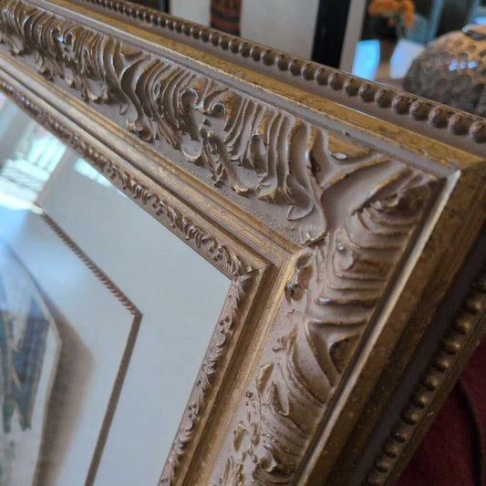Close-up of an ornate gold mirror frame with intricate detailing.