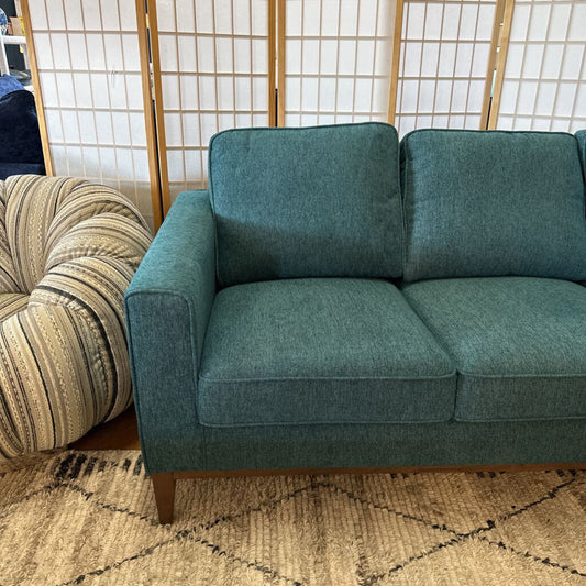 Teal sofa in a room with a striped cushion and wooden screen