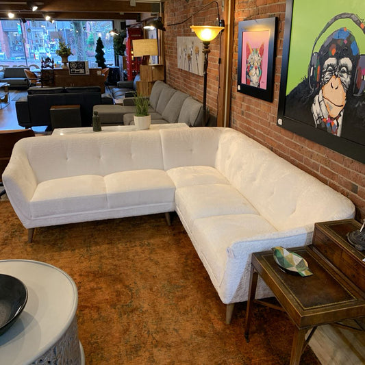 White sectional sofa in a living room with a brick wall and artwork.