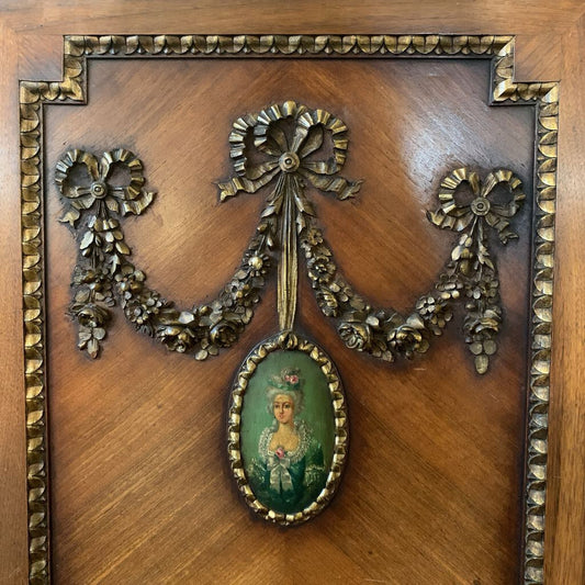 Decorative wooden panel with a gold ribbon and portrait in a wooden frame.